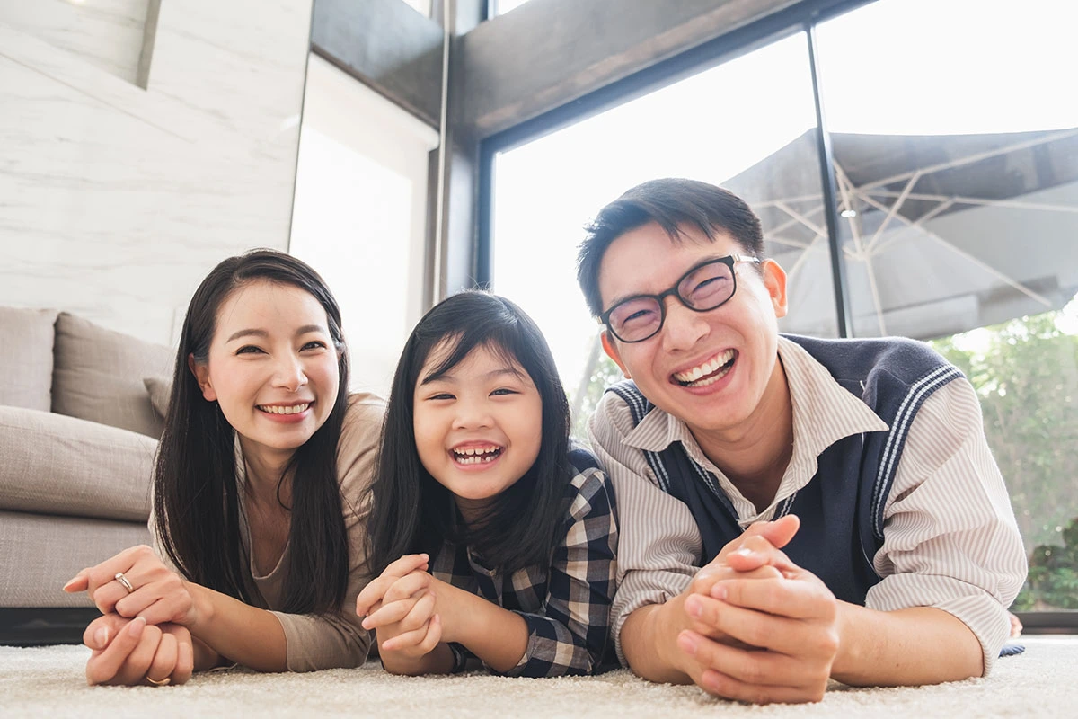 Smiling parents and child lying on the floor at home