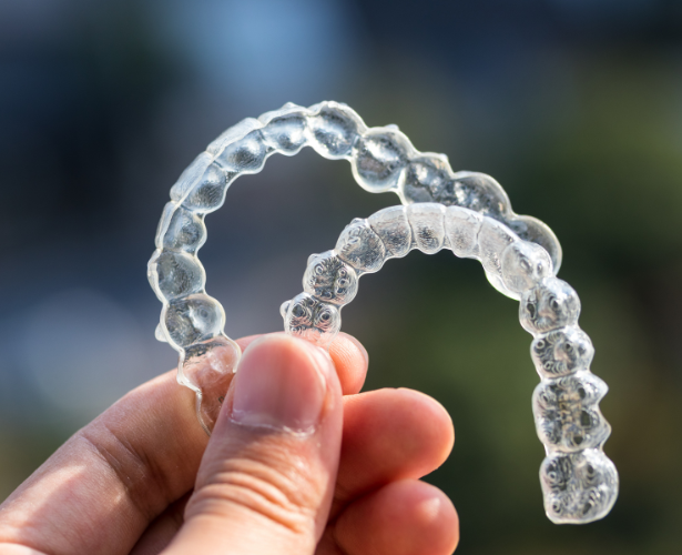 Hand holding two clear orthodontic aligners