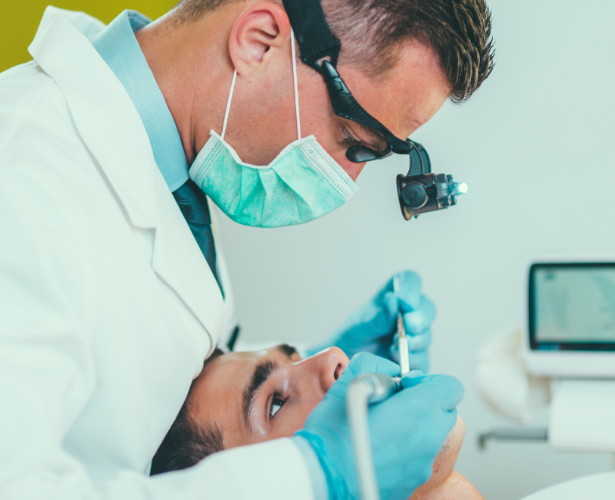 Dentist performing root canal treatment using magnification loupes